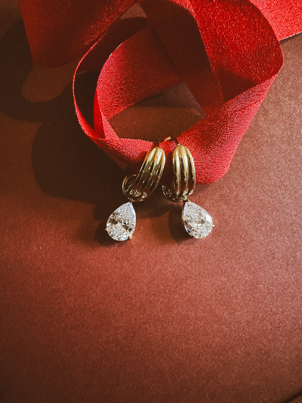 Tear drop Huggie Hoops On maroon background