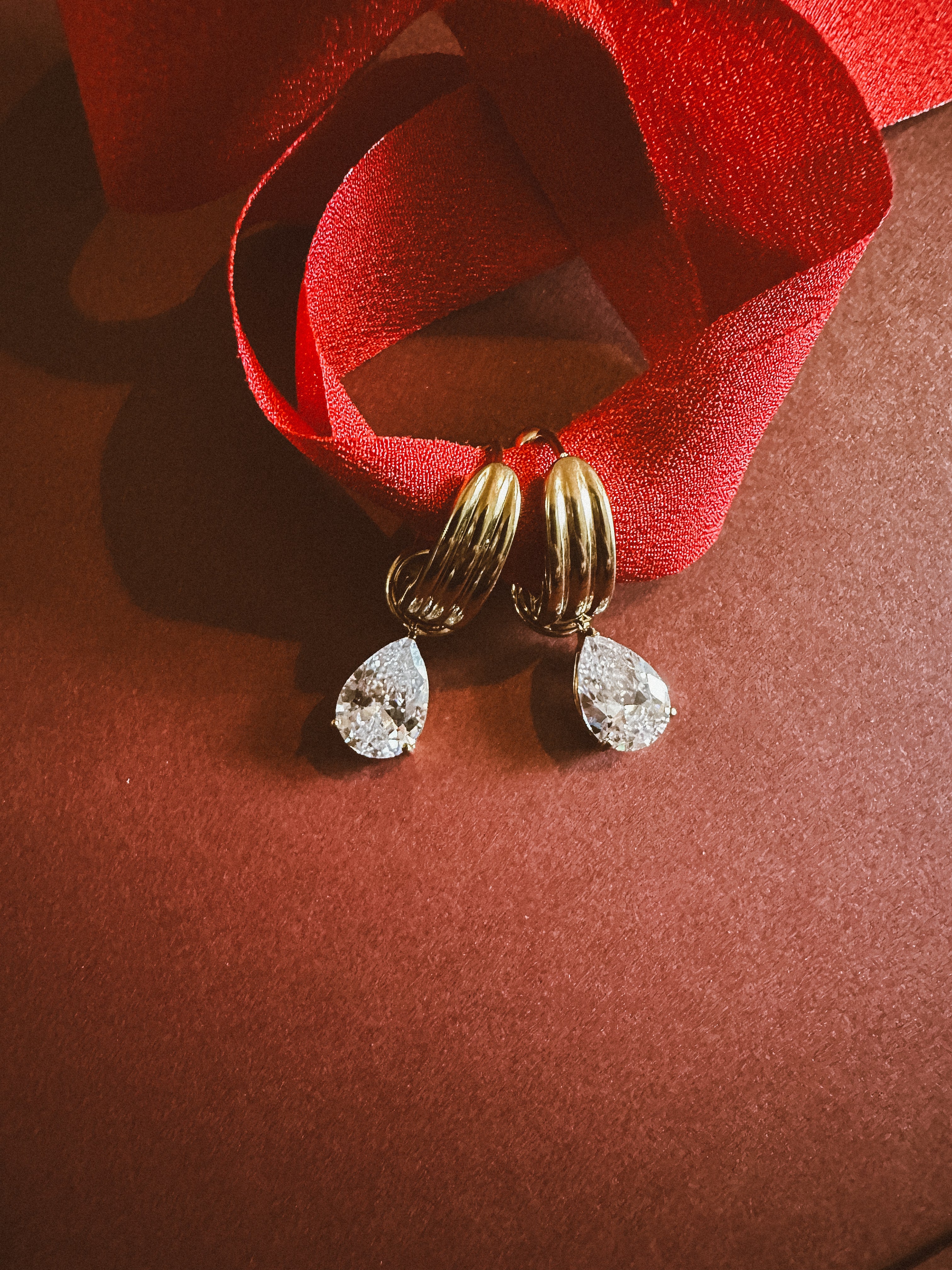 Tear drop Huggie Hoops On maroon background