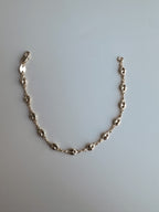 Gold chain bracelet on a light gray background