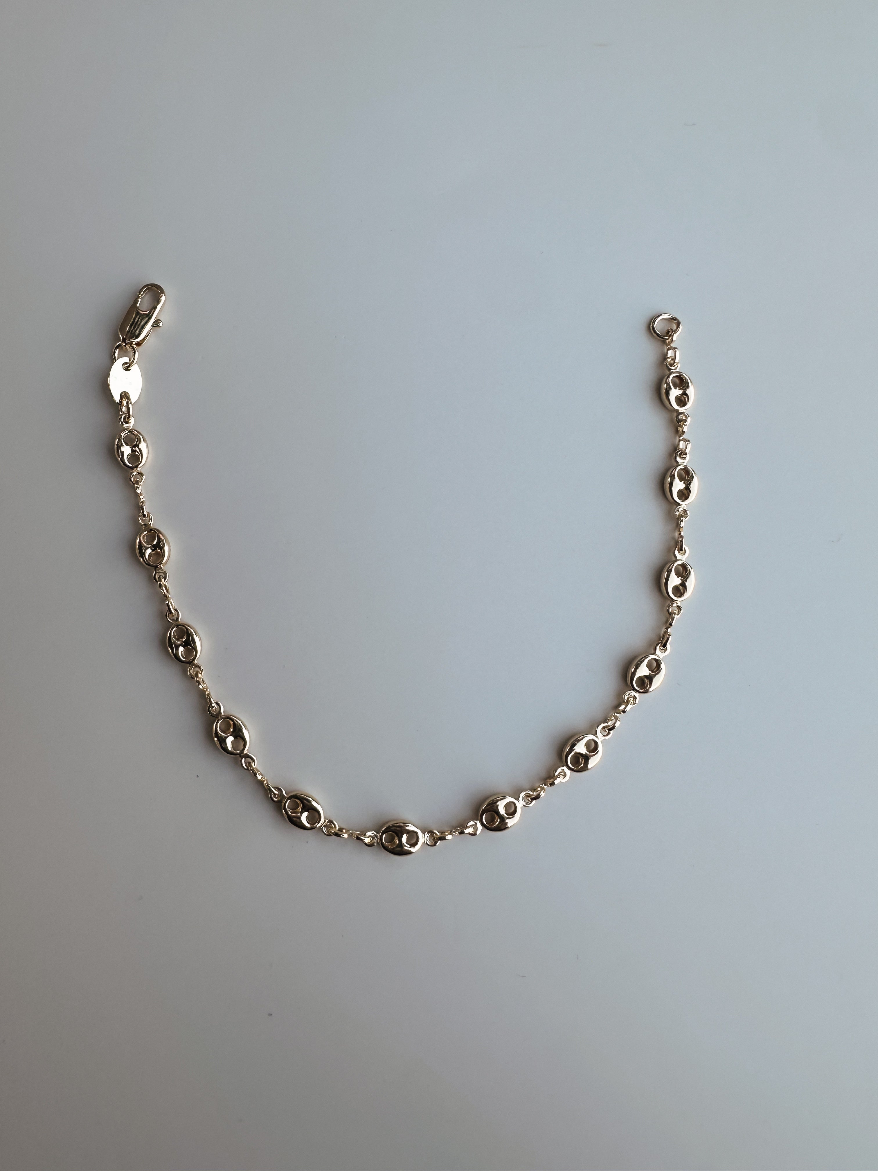 Gold chain bracelet on a light gray background