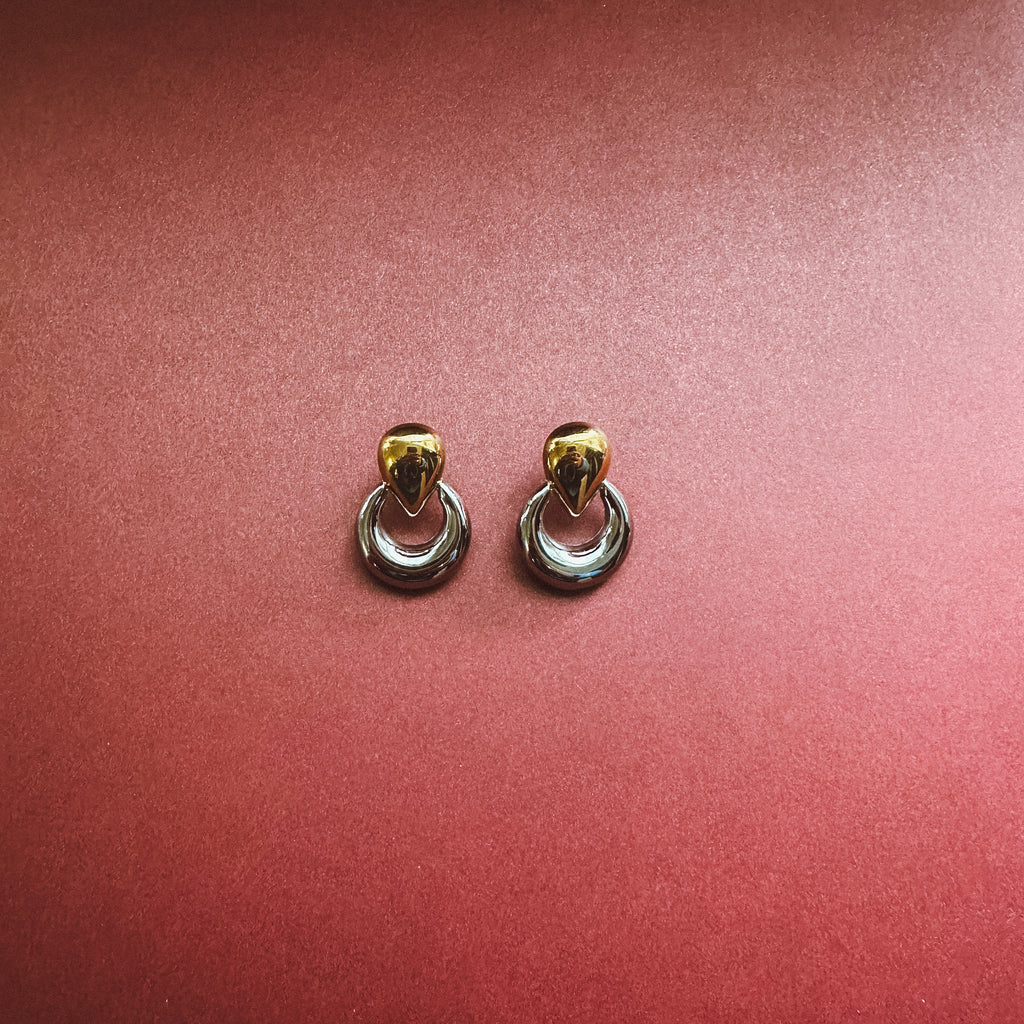 Two tone earrings on maroon background 