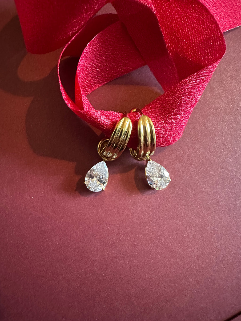 Tear drop Huggie Hoops On maroon background