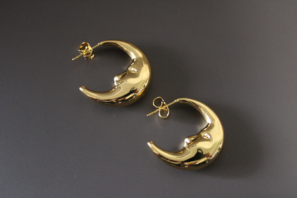 Gold crescent moon-shaped earrings on a dark gray background