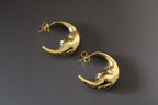 Gold crescent moon-shaped earrings on a dark gray background