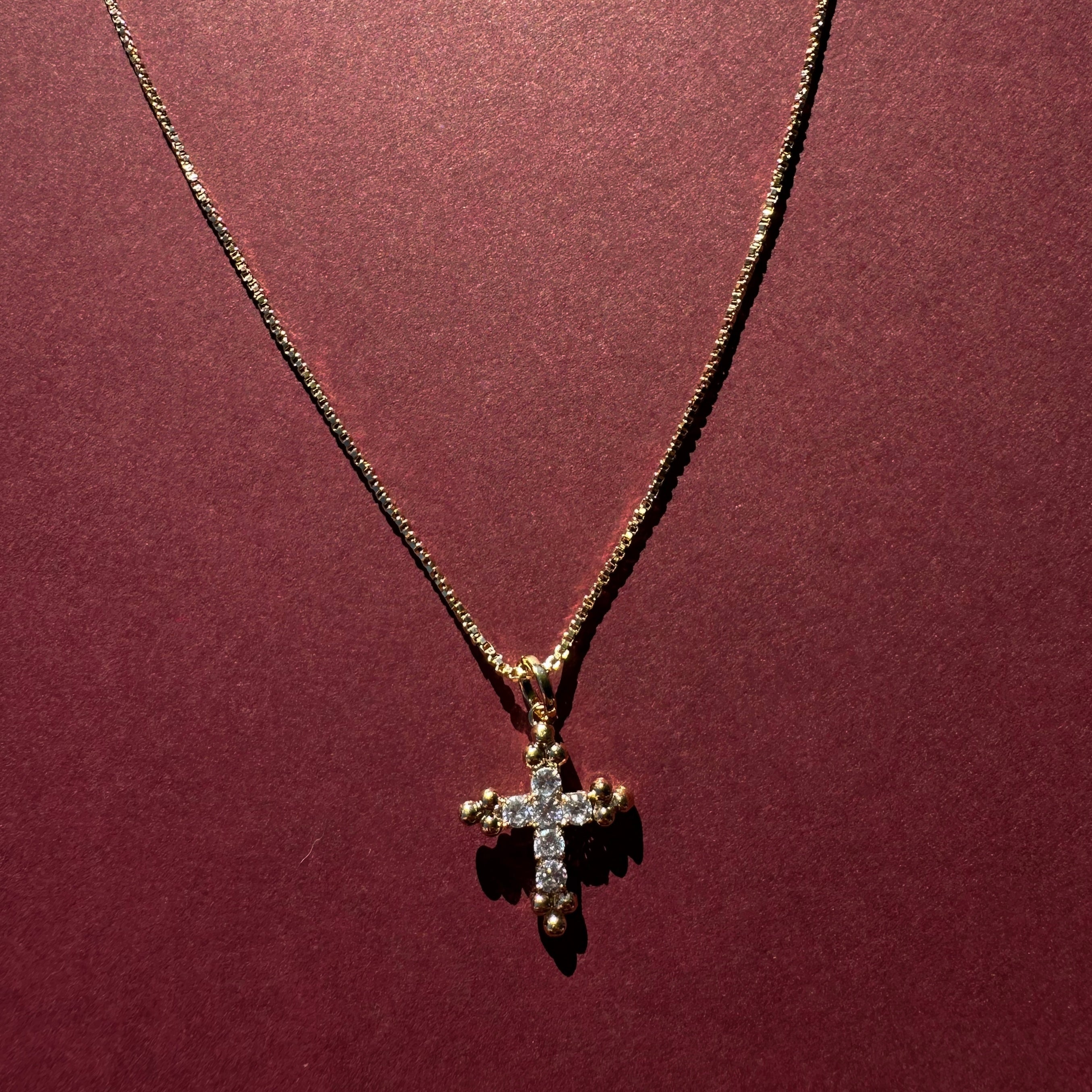 Dainty Cross necklace with maroon background 
