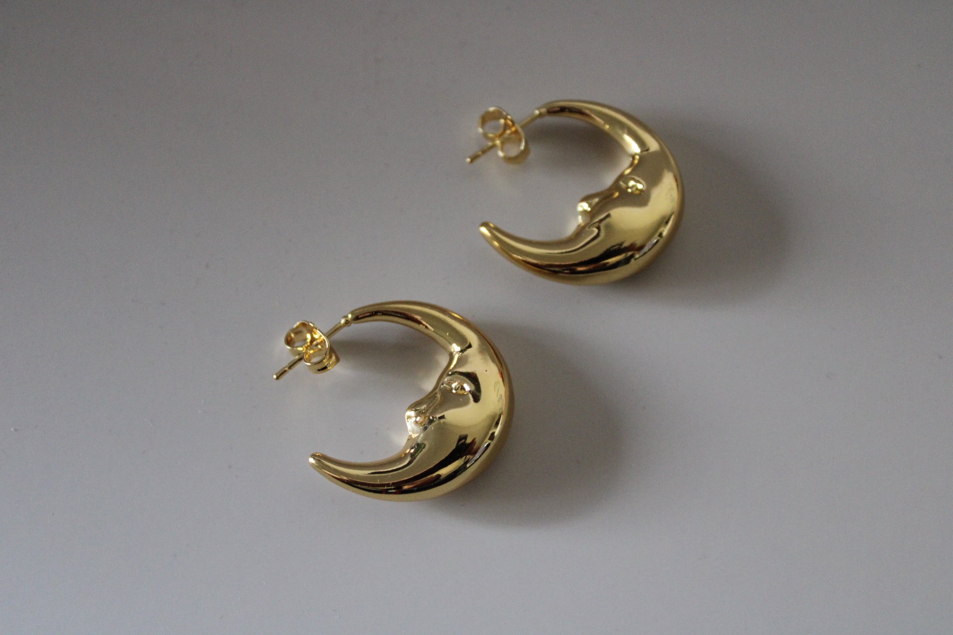 Gold crescent moon-shaped earrings on a light gray background