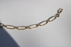 Gold chain bracelet on a light gray background