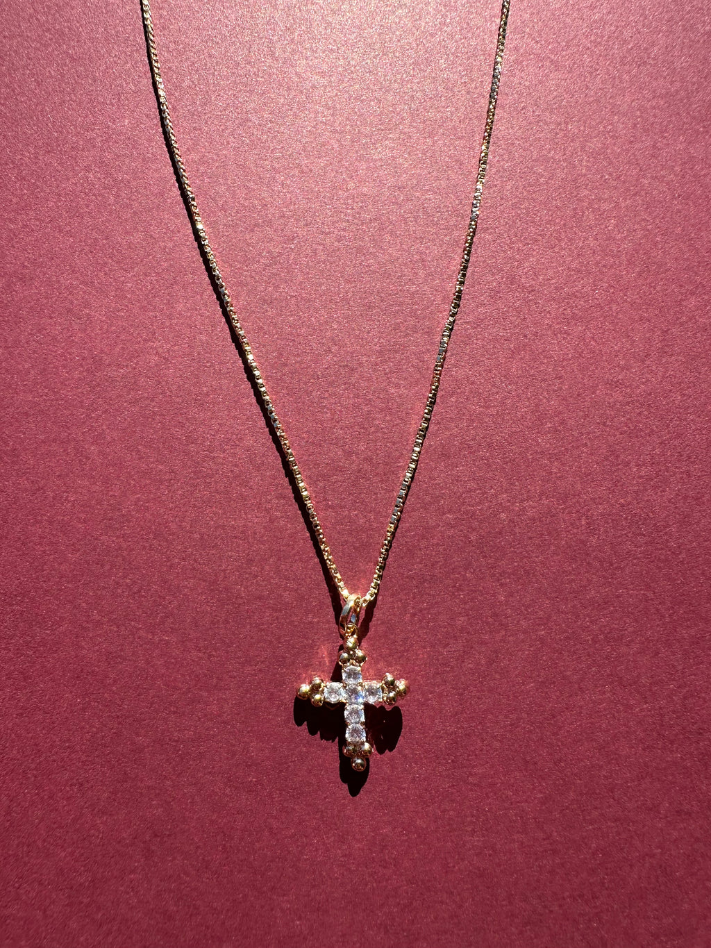 Dainty Cross necklace with maroon background 