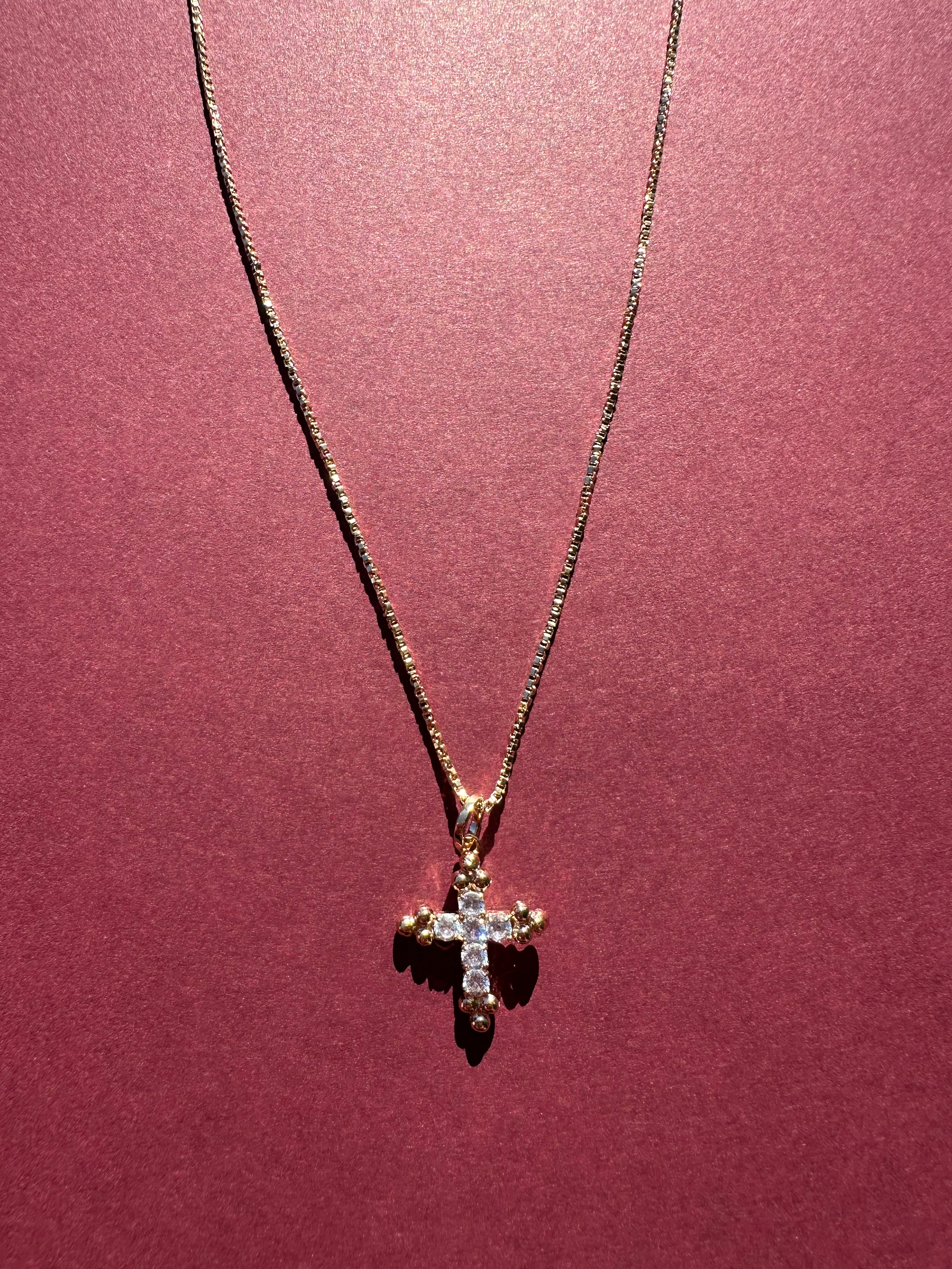 Dainty Cross necklace with maroon background 