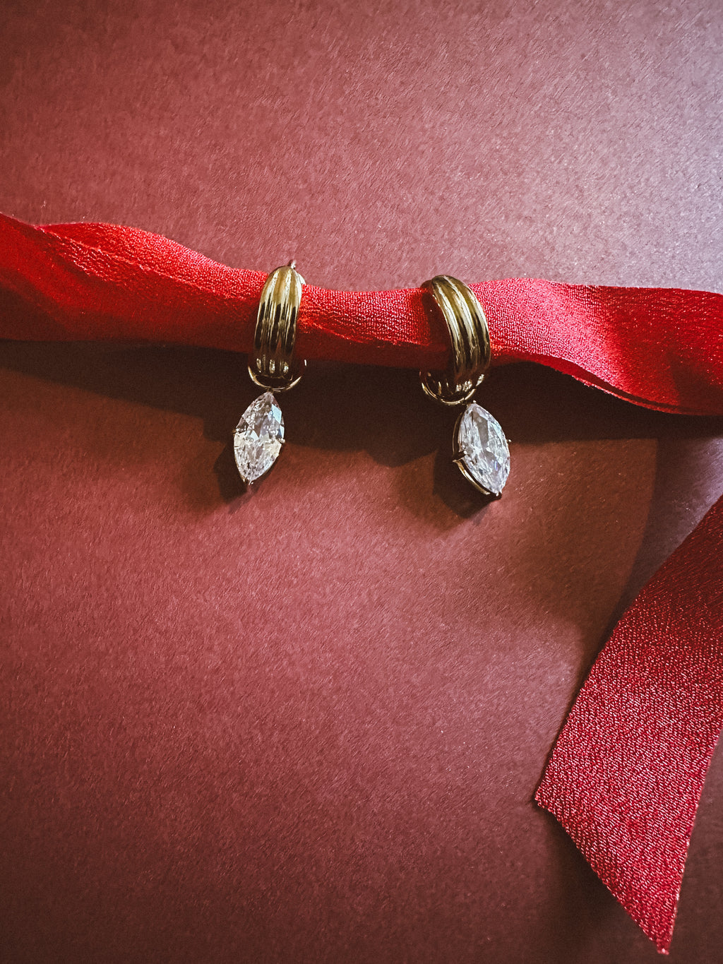 Marquise Huggie Hoops On maroon background 
