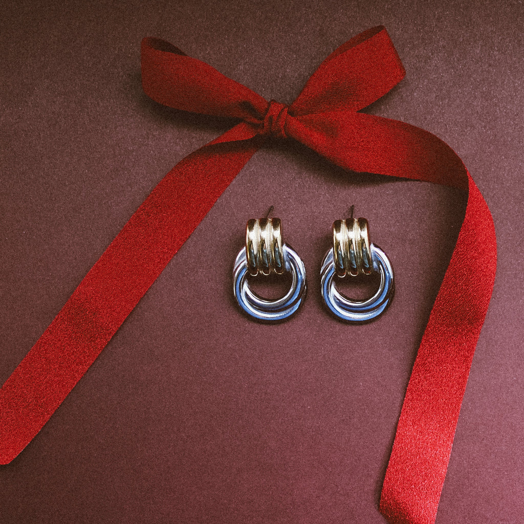 Bold Statement Stud Earrings Two Tone in a maroon background
