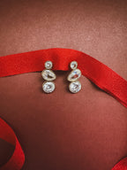 bezel drop earrings on a dark red background