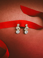 bezel drop earrings on a dark red background